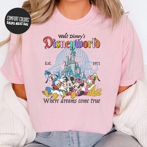 A woman wearing a pink t-shirt with a Disney World logo and text.