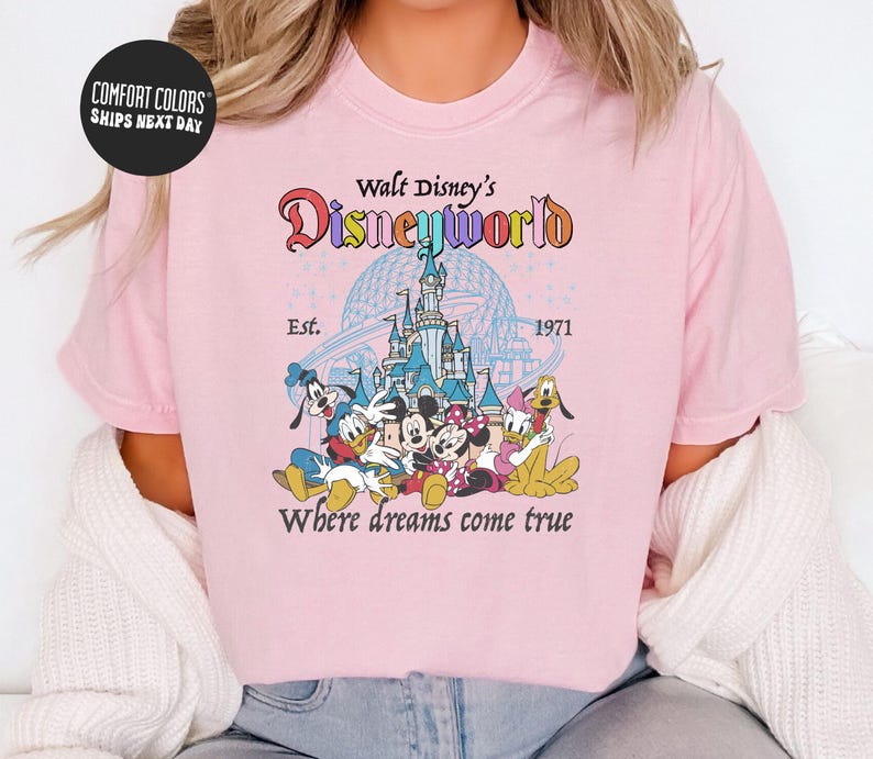 A woman wearing a pink t-shirt with a Disney World logo and text.