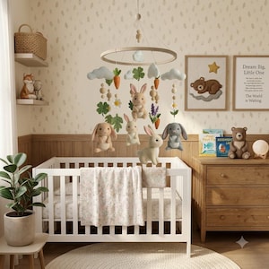 May include: A nursery mobile featuring a circular wooden frame with hanging felt elements including four rabbits in shades of brown and gray, orange carrots, green clover leaves, white daisies, purple lavender sprigs, and light gray clouds.