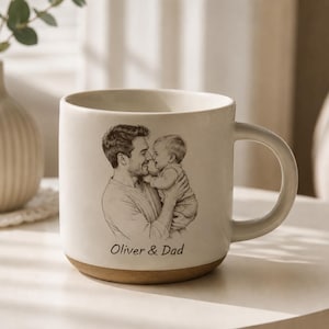 Peut inclure: Mug en céramique crème avec une base marron et une grande anse. La tasse présente une esquisse en noir et blanc d'un père tenant un bébé, avec le texte "Oliver & Dad" sous l'image. Un article décoratif.