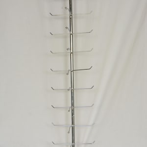 Pode incluir: Um expositor vertical de metal prateado com uma haste central e dez bra&ccedil;os horizontais que se estendem de cada lado. A estrutura inclui um suporte de montagem circular no topo e uma base curva na parte inferior para estabilidade.