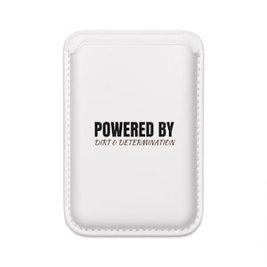 May include: White phone case with the text "POWERED BY DIRT & DETERMINATION" in black and brown. The case has a stitched border and a rounded top edge.