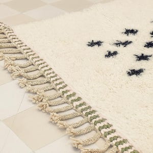 a close-up view of a white shag rug with a decorative fringe on the edge.