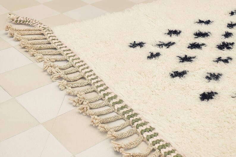 a close-up view of a white shag rug with a decorative fringe on the edge.