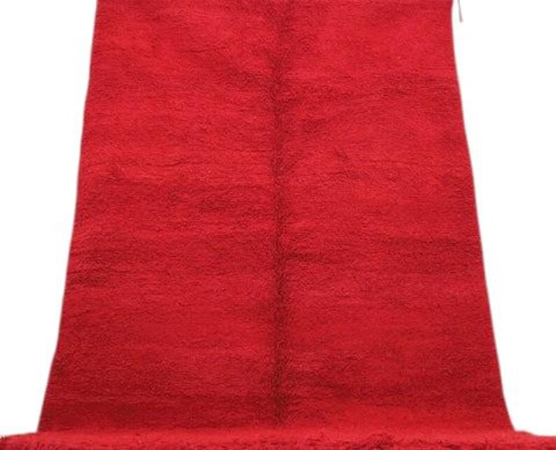 A large, red, shaggy rug is displayed against a white background.