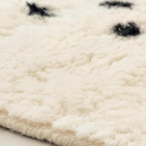 a close-up view of a fluffy, white carpet with small black spots on it.