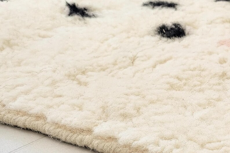 a close-up view of a fluffy, white carpet with small black spots on it.