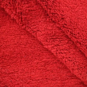 A close-up view of a red, fluffy fabric, possibly a blanket or towel, with a textured and soft appearance.