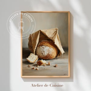 May include: A framed print of a loaf of bread in a paper bag, with a piece broken off. The print has a vintage aesthetic, with the words "Atelier de Cuisine" at the bottom and a circular logo at the top.