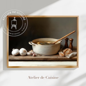 May include: A framed still life print featuring a white pot of soup with a wooden spoon, garlic, bread, and salt and pepper shakers. The print has a vintage aesthetic and the text "Atelier de Cuisine" is at the bottom.