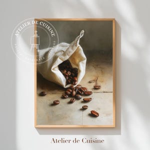 May include: A framed print of a still life featuring a canvas bag spilling coffee beans onto a light-colored wooden surface. The print has a vintage aesthetic, with the text "Atelier de Cuisine" at the bottom and a circular logo at the top.