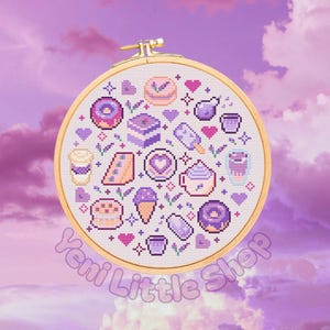 Könnte beinhalten: Ein Kreuzstich-Stickrahmen mit einem Dessert-Motiv in Lila, Rosa und Gelb. Das Design umfasst Donuts, Eis, Kuchen und Kaffeetassen. Der Text "Yemi Little Shop" ist unten sichtbar.
