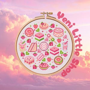 May include: A circular wooden embroidery hoop containing a cross-stitch pattern of various pink and green desserts, including cakes, donuts, and strawberries, with the text "yeni Little Shop" written in pink letters along the right side.