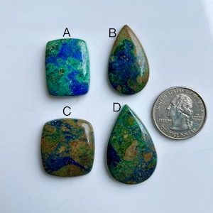May include: Four azurite and malachite gemstone cabochons in different shapes, including rectangular and teardrop. The gemstones show a mix of blue, green, and brown colours. A U.S. quarter coin is included for size reference.
