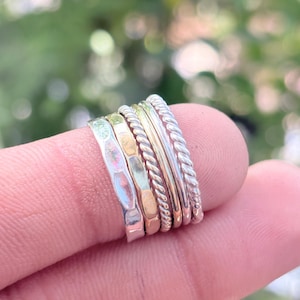 May include: A white ceramic mug with a black handle and the text "But First, Coffee" in a black, handwritten-style font. The mug is on a white surface.