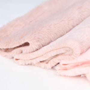Soft pink faux rex rabbit fur fabric with short pile made of plush synthetic fibers. Use it for sewing costume accents, plush crafts, or fursuit detailing. With a gentle feel and rich color, this 0.4–0.6 in pile fur brings luxury texture to small projects requiring softness and warmth.