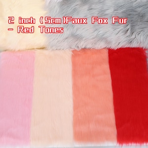 May include: Faux fox fur in red tones, 2 inches thick. The image displays various shades of red, pink, and cream-colored faux fur. The text in the image reads "2 inch (5cm) Faux Fox Fur - Red Tones."