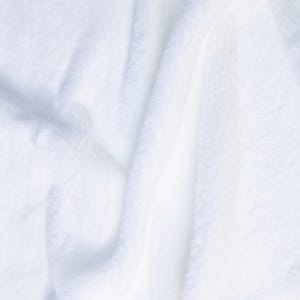May include: Close-up of a soft, white, fluffy blanket. The fabric has a plush texture with visible folds and shadows, creating a sense of depth. The overall appearance is clean and inviting, suggesting comfort and warmth.