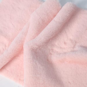 Plush faux fur fabric in blush pink tones with a low 1–1.5 cm pile for detailed sewing. Perfect for soft trims, plush details, or lining for costumes and fursuits. Easy to cut, sew, and shape, this synthetic fabric mimics real rabbit fur while being animal-free and incredibly soft.