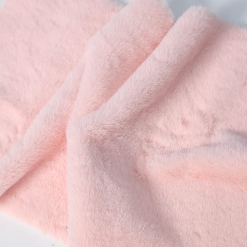 Plush faux fur fabric in blush pink tones with a low 1–1.5 cm pile for detailed sewing. Perfect for soft trims, plush details, or lining for costumes and fursuits. Easy to cut, sew, and shape, this synthetic fabric mimics real rabbit fur while being animal-free and incredibly soft.