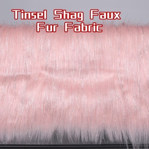 Könnte beinhalten: Rosa Kunstfellstoff mit silbernen Lametta-Strähnen. Der Stoff hat einen langen Shag-Flor und den Text "Tinsel Shag Faux Fur Fabric" in roter Schrift.