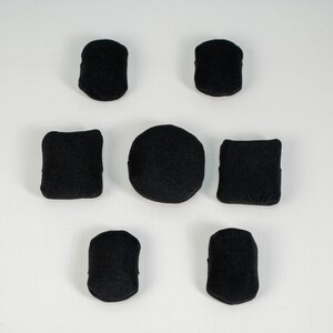 May include: A set of seven black fabric patches arranged in a circular pattern. The collection includes two rounded rectangular patches at the top, two square patches in the middle, one circular patch in the center, and two rounded patches at the bottom.