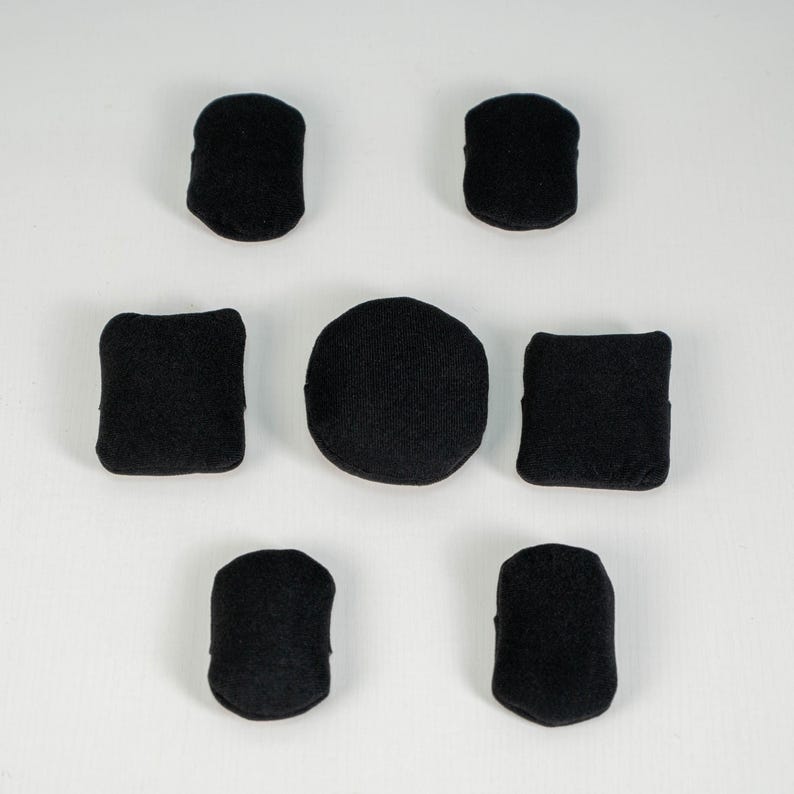 May include: A set of seven black fabric patches arranged in a circular pattern. The collection includes two rounded rectangular patches at the top, two square patches in the middle, one circular patch in the center, and two rounded patches at the bottom.