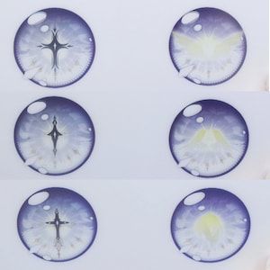 May include: Six round, blue-purple eye designs with intricate inner details. Each eye features a cross or angel wing design in white and gold, with a light blue and yellow gradient. The eyes are set against a white background.