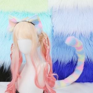 Può includere: Un set di fascia con orecchie da gatto, parrucca e coda dai colori pastello. La fascia presenta un fiocco con accenti rosa, gialli e blu. La parrucca ha capelli biondi con ombre rosa. La coda è a righe con colori pastello.