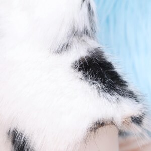 Cow patterned faux fur neck piece made for cosplay and furry events, boasting black and white contrasting spots. The inner lining adds softness and prevents heat buildup. Designed to pair with other fursuit components like ears, tails, or hooves for a complete and harmonious animal-themed costume set.
