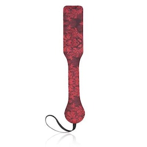 Puede incluir: Una paleta roja con un estampado floral. La paleta tiene una cabeza rectangular, un mango largo y una base redondeada. Un lazo negro está unido a la base. La paleta está diseñada para el juego de impacto.