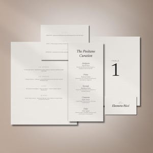 Könnte beinhalten: Eine Sammlung von cremefarbenen Hochzeitspapeterie-Artikeln, bestehend aus einem großen Menü, einem schmalen, hohen Menü mit dem Titel The Positano Curation, einer kleinen quadratischen Karte, einer Tischnummer 1 und einer Namenskarte Eleonora Ricci.