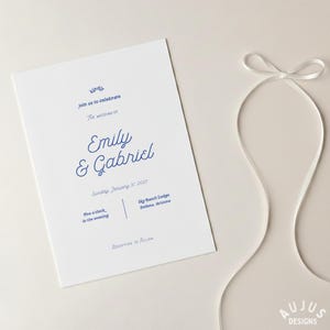 May include: A white wedding invitation with blue text. The invitation reads "kindle join us to celebrate THE WEDDING OF Emily & Gabriel Sunday, January 31 2027". The invitation also includes the time and location of the wedding.