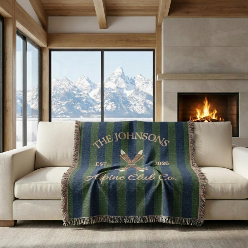 Personalized alpine blanket showing woven cotton texture in preppy Navy Green striped heritage design, alpine ski emblem and fringe detail, custom family name, cabin name ski chalet home decor