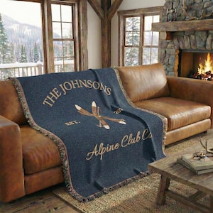 Personalized alpine blanket showing woven cotton texture in Navy with fringes, alpine ski emblem, custom family name, established year, cabin name ski chalet home decor livingroom