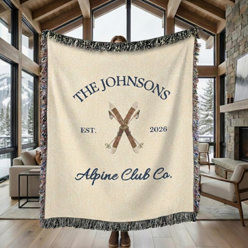 personalized alpine blanket showing woven cotton texture in elegant cream color, alpine ski emblem and fringe detail, personalized family name, custom alpine location or cabin