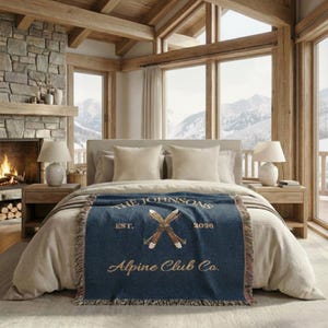 Personalized alpine blanket showing woven cotton texture in classy navy, alpine ski emblem and fringe detail, custom family name, cabin name ski chalet home decor bedroom