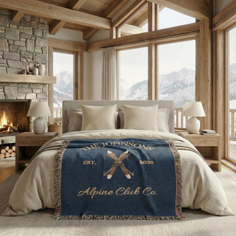 Personalized alpine blanket showing woven cotton texture in classy navy, alpine ski emblem and fringe detail, custom family name, cabin name ski chalet home decor bedroom