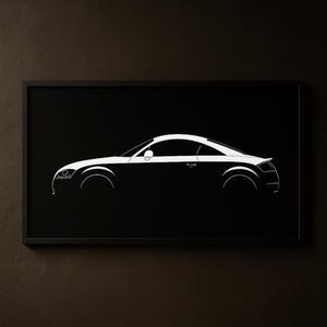 May include: A framed black and white print featuring a side profile of a sports car. The car's silhouette is rendered in white against a black background, showcasing its sleek design. The print is encased in a black frame.