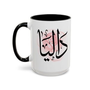 May include: White ceramic mug with a black handle and interior. The mug features a pink rose design and black Arabic calligraphy. A stylish and personalized coffee mug.