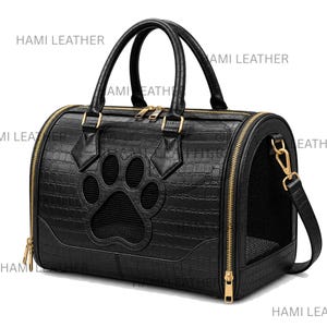 May include: A black pet carrier bag with a crocodile-embossed texture, featuring gold-tone zippers and hardware. The front panel displays a large paw-print shaped mesh window. The text HAMI LEATHER is visible multiple times across the image.