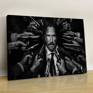 May include: Black and white canvas print featuring a man surrounded by multiple hands holding guns. The man is in a suit and tie, with a serious expression. The image is a dramatic, action-oriented portrait.