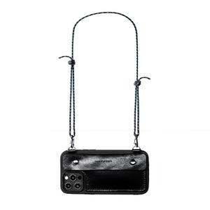 May include: Black leather phone case with a crossbody strap. The case has a flap closure and is secured with silver-tone rivets. The strap is a black and green rope design. The phone case has a camera cutout and the text "needlework".