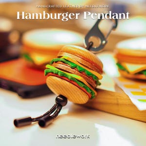 Puede incluir: Colgante de hamburguesa de madera artesanal con cierre metálico. El colgante presenta capas de una hamburguesa, incluyendo pan, carne, lechuga y queso. El texto "Hamburger Pendant" se muestra arriba.