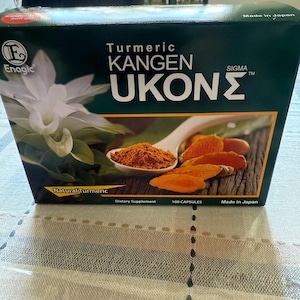 May include: A box of Turmeric Kangen Ukon Sigma dietary supplements. The box is dark green with white text and a picture of turmeric powder and slices. The box also features the Enagic logo and states "Made in Japan."
