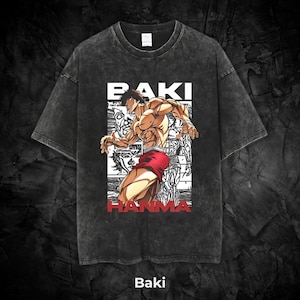 May include: Dark gray t-shirt featuring a muscular anime character in red shorts. The shirt has the text "BAKI HANMA" in white and red, with the word "Baki" at the bottom. The shirt has a vintage, washed look.