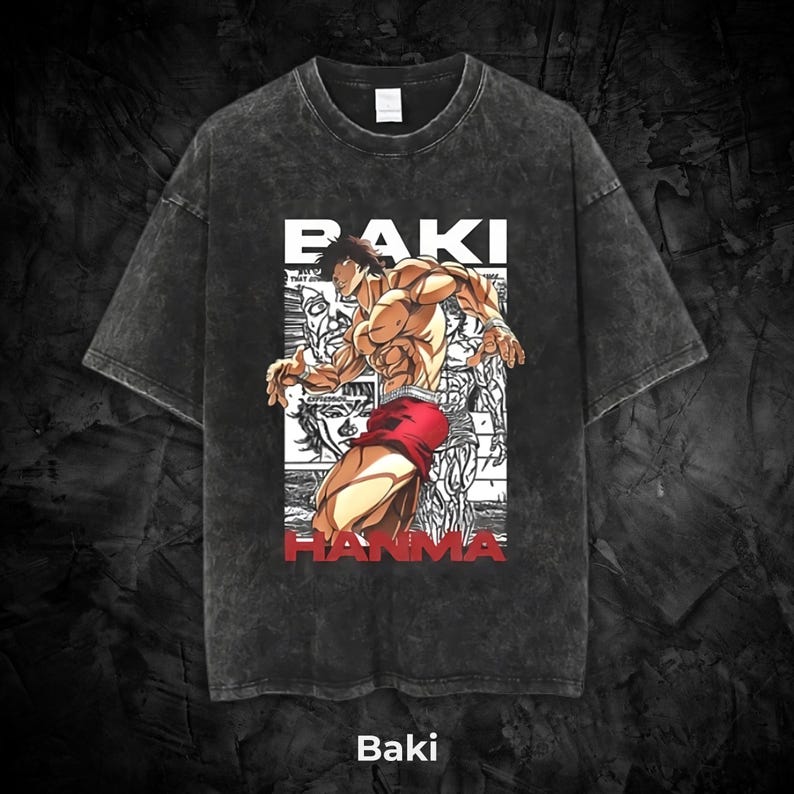May include: Dark gray t-shirt featuring a muscular anime character in red shorts. The shirt has the text "BAKI HANMA" in white and red, with the word "Baki" at the bottom. The shirt has a vintage, washed look.