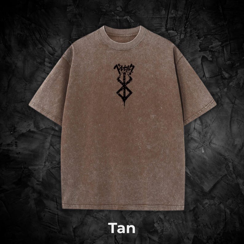May include: Tan-colored t-shirt with a crew neck and short sleeves. The shirt features a black graphic design on the front, along with Japanese text. The word "Tan" is printed at the bottom of the image.