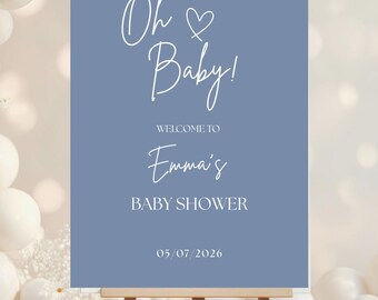 Pode incluir: Uma placa de chá de bebé numa tela de madeira. A placa é azul empoeirado e apresenta as palavras "Oh Baby!" e "Bem-vindo ao Chá de Bebé da Emma" em letras brancas. A data 05/07/2026 também é exibida. O fundo tem balões brancos.
