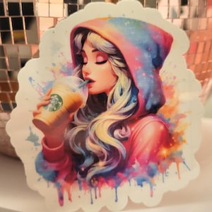 Puede incluir: Una pegatina con una ilustración en acuarela de una persona con una sudadera con capucha con temática de galaxia, bebiendo de un vaso de Starbucks. El diseño utiliza rosa, azul y amarillo, con un efecto de arte salpicado.
